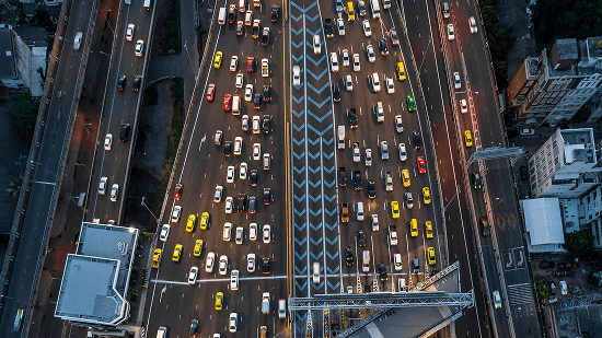 Aerial view of a multilane city highway filled with heavy traffic, including taxis and cars, during rush hour.
