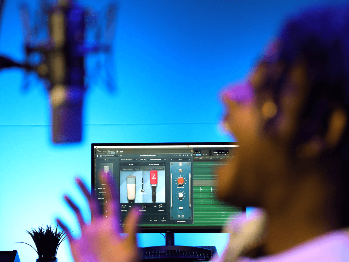 Vocalist recording in a studio with the Virtual Microphone System plugin visible on screen, showing Slate Digital mic models and controls during a session.